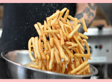 Fries being tossed in salt or seasoning.